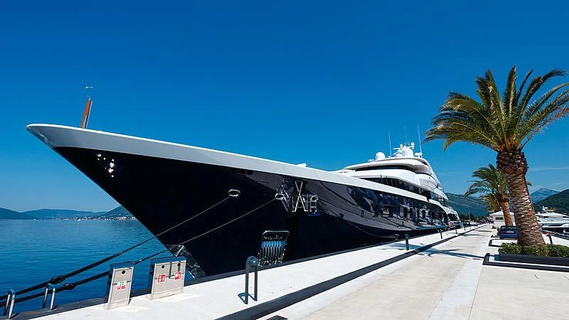 a large black and white boat on a dock by a body of water aboard SYMPHONY Yacht for Sale