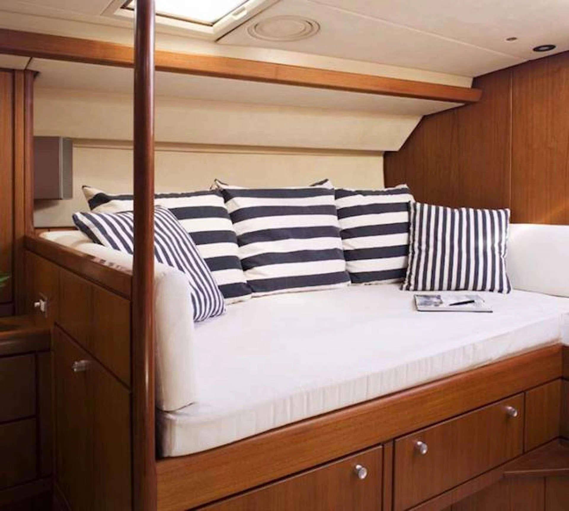 a bed with white and black striped pillows aboard ABEON Yacht for Charter