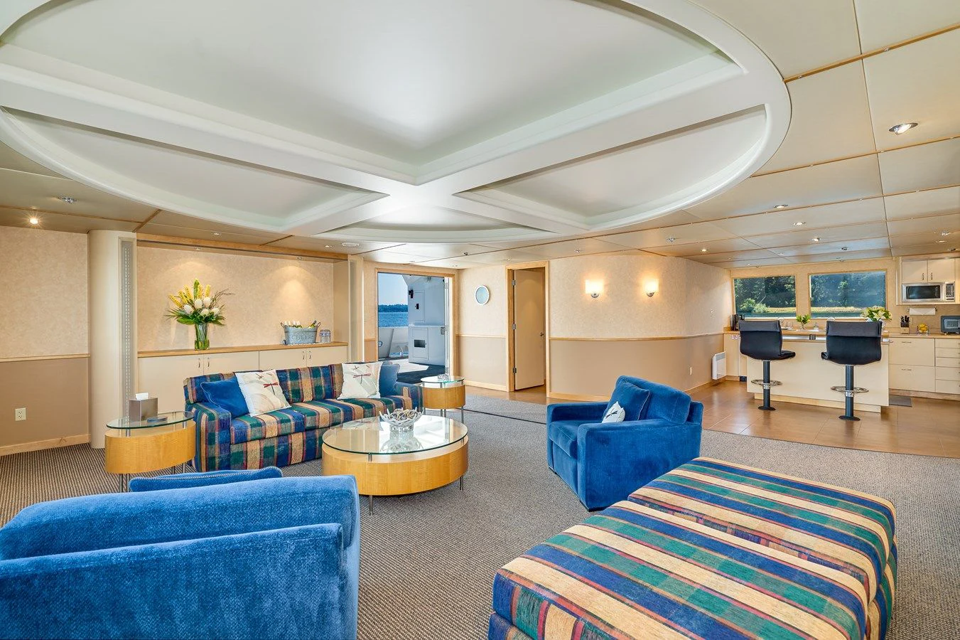 a large living room with a blue couch and a table aboard DRAGONFLY Yacht for Sale