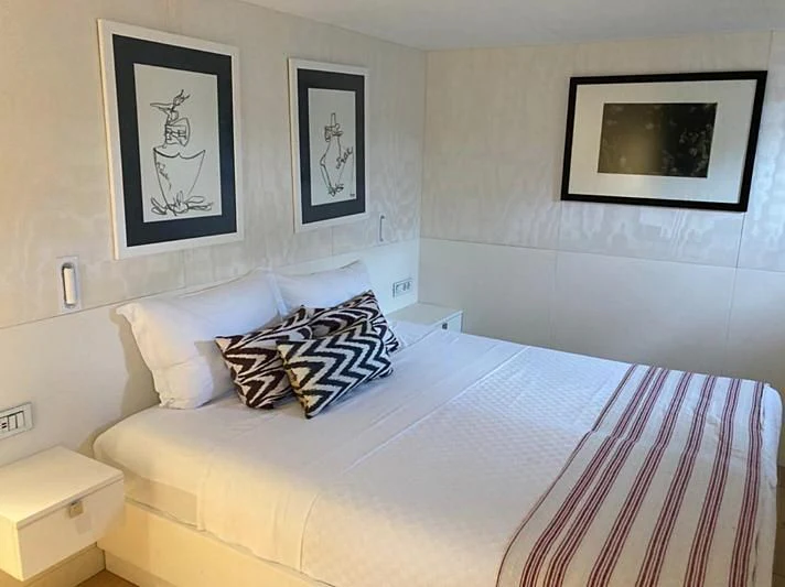 a bed with a white sheet and a picture on the wall aboard VIKA Yacht for Sale