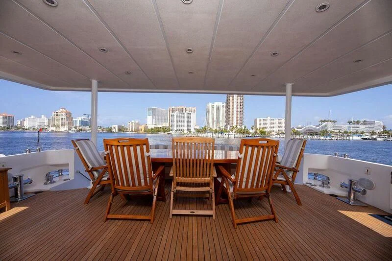 a wood table with chairs on a deck overlooking a city aboard LADY GERTS Yacht for Sale