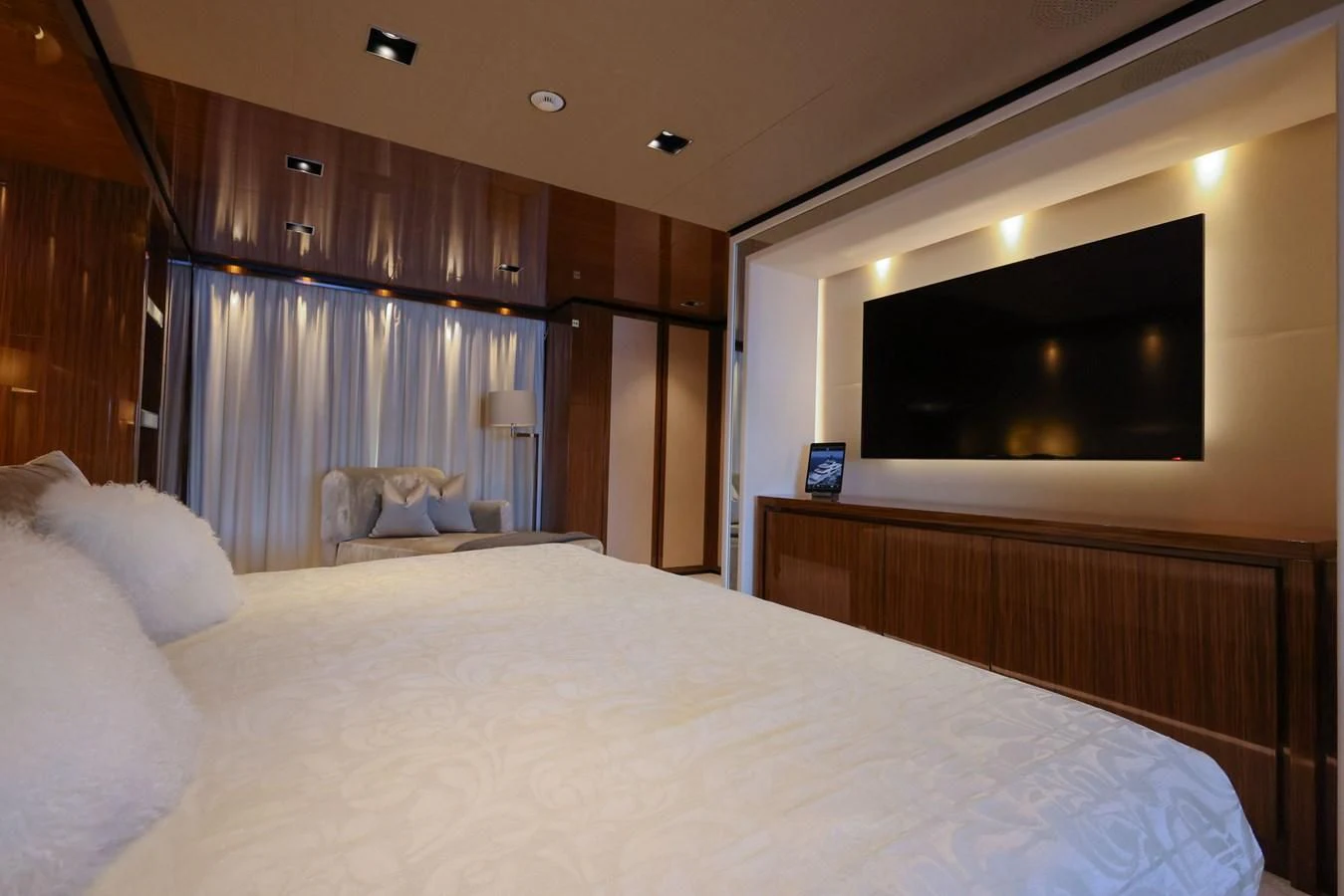 a bed with a white sheet and a television on the wall aboard MEDIALLY Yacht for Sale