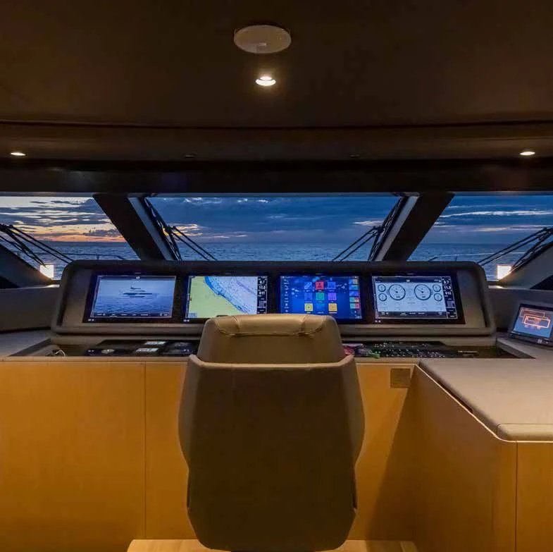 a coffee cup on a desk in a room with a computer and a large window aboard SPICA Yacht for Sale