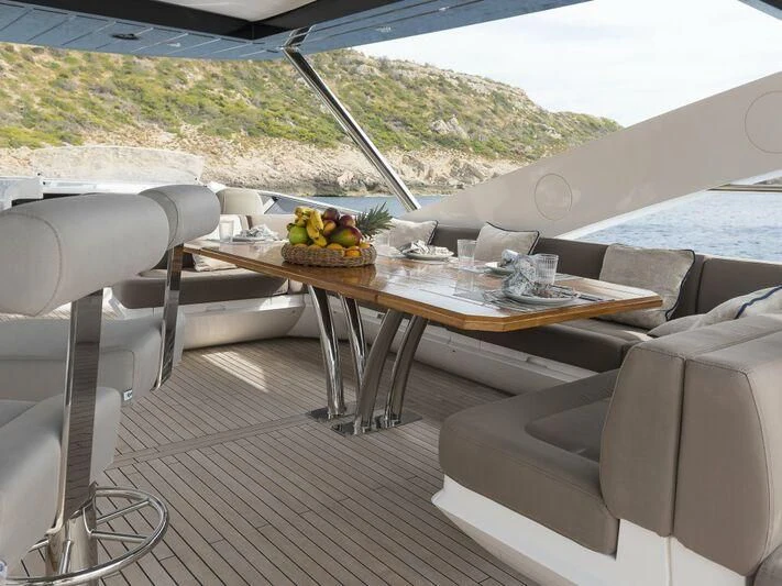 a table with chairs and a couch on a deck with a view of a mountain range aboard AFTER 8 II Yacht for Sale