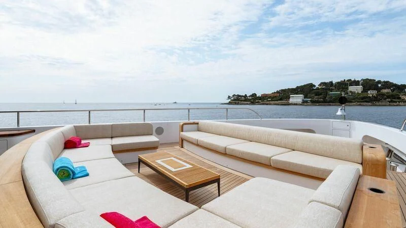 a couch and a table on a balcony overlooking a body of water aboard TOSUN Yacht for Sale