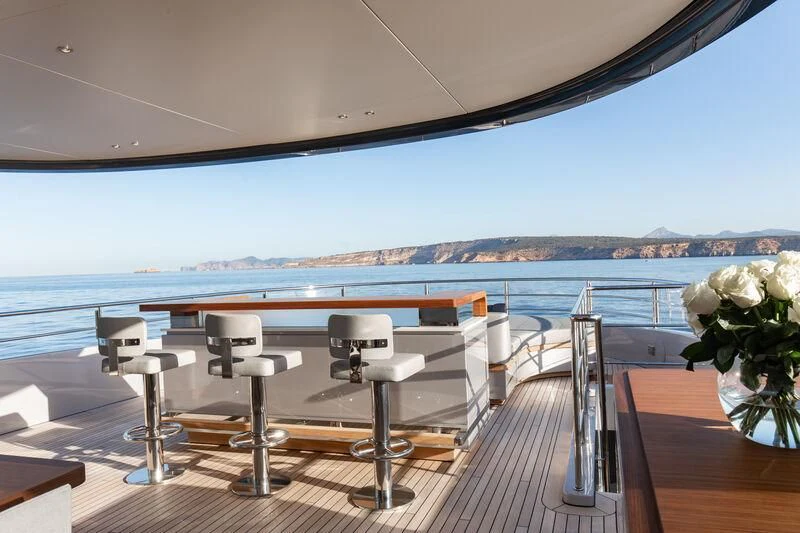 a room with a table and chairs on a deck overlooking a body of water aboard TOSUN Yacht for Sale
