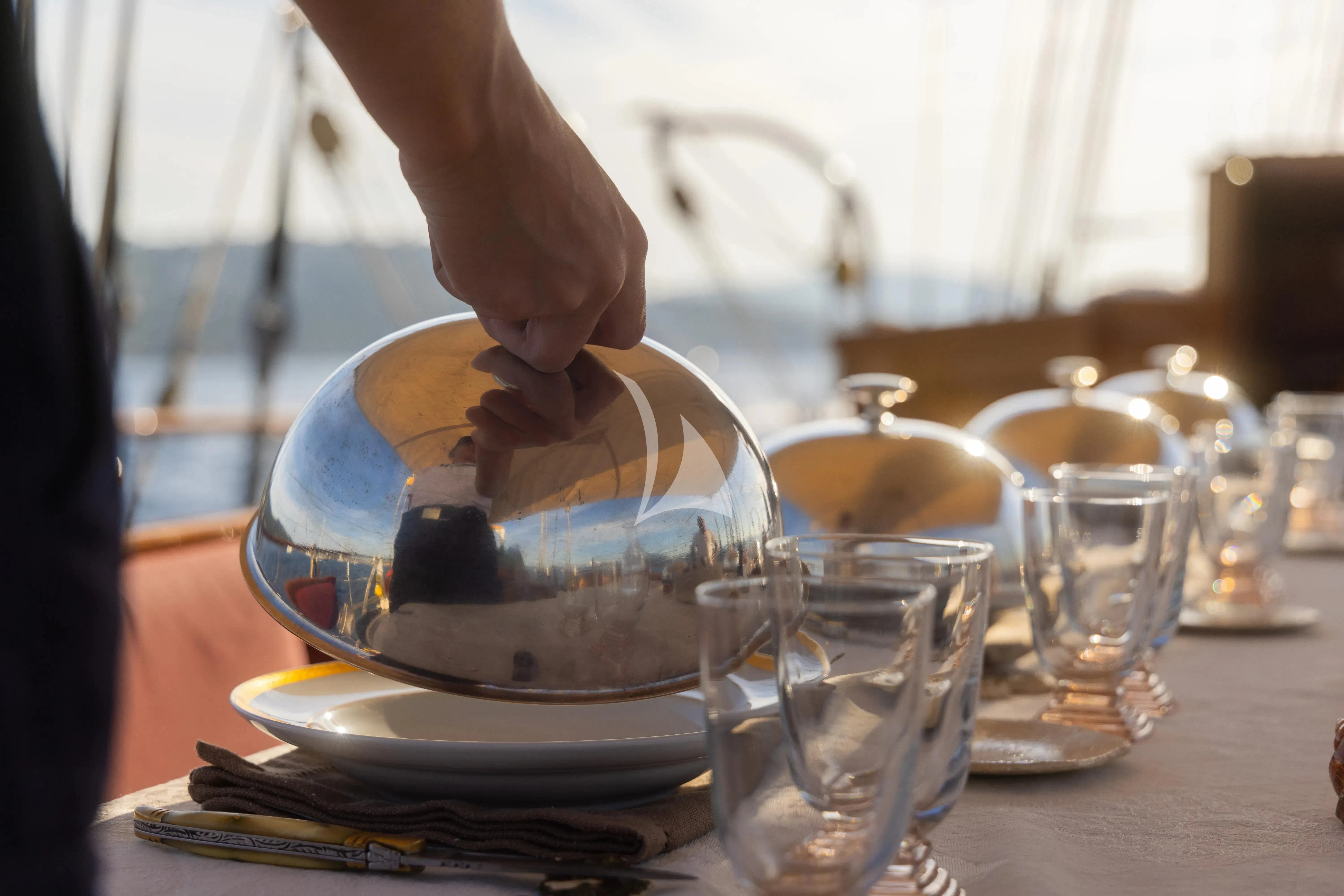 a hand pouring a liquid into a glass aboard TRINAKRIA Yacht for Charter