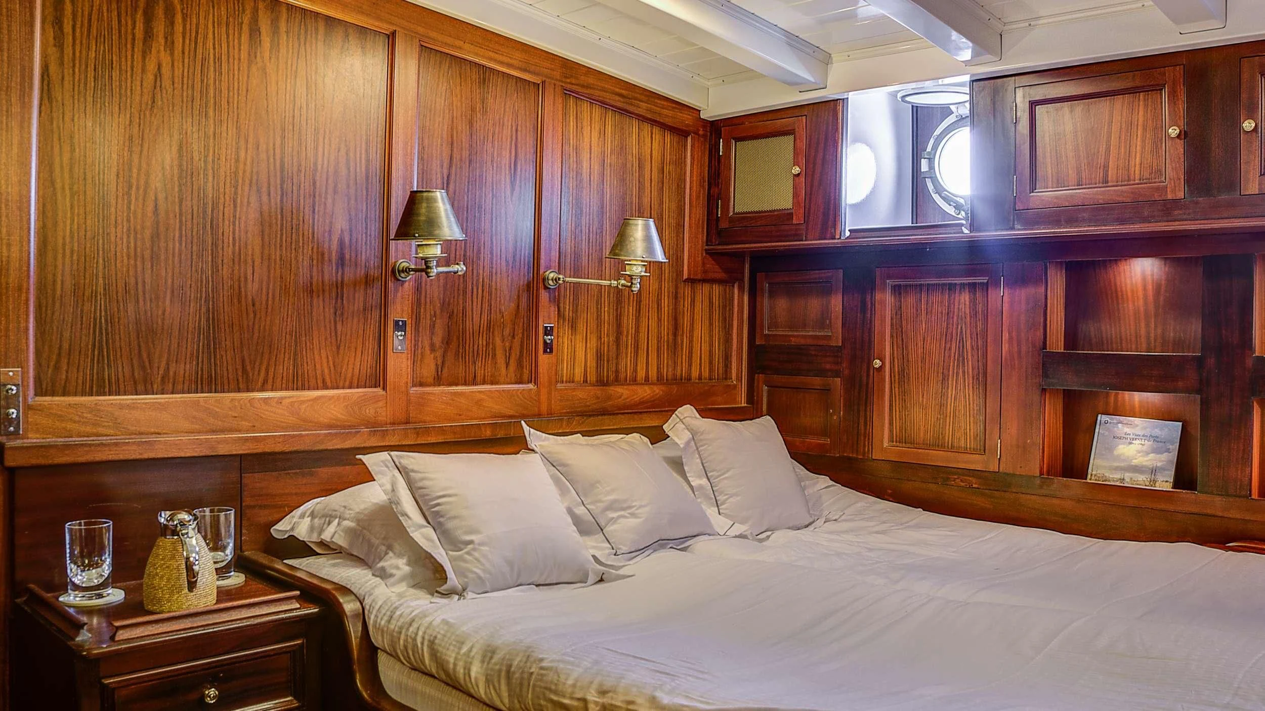 a bed with white sheets and pillows aboard TRINAKRIA Yacht for Charter
