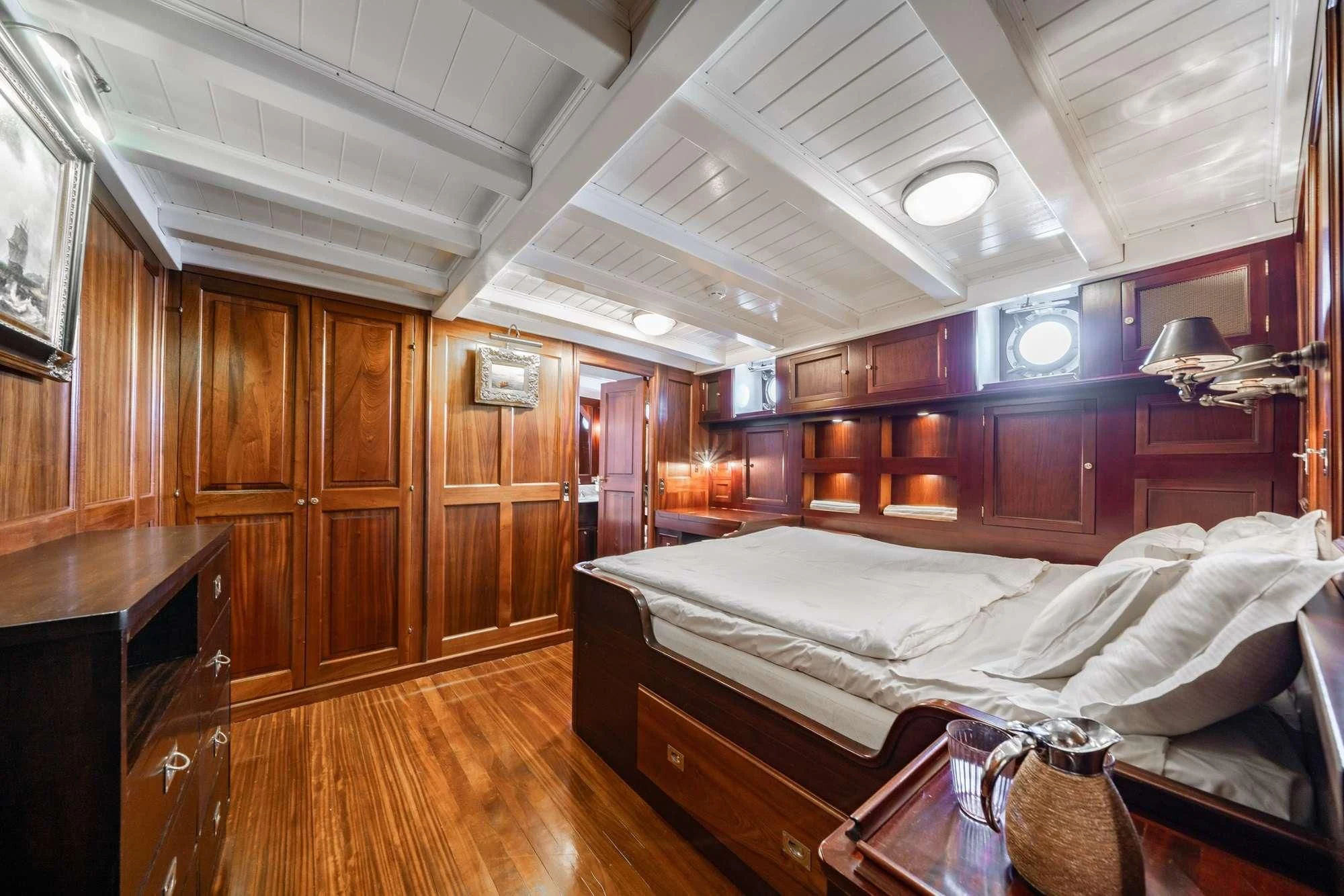 a bedroom with wooden furniture aboard TRINAKRIA Yacht for Charter