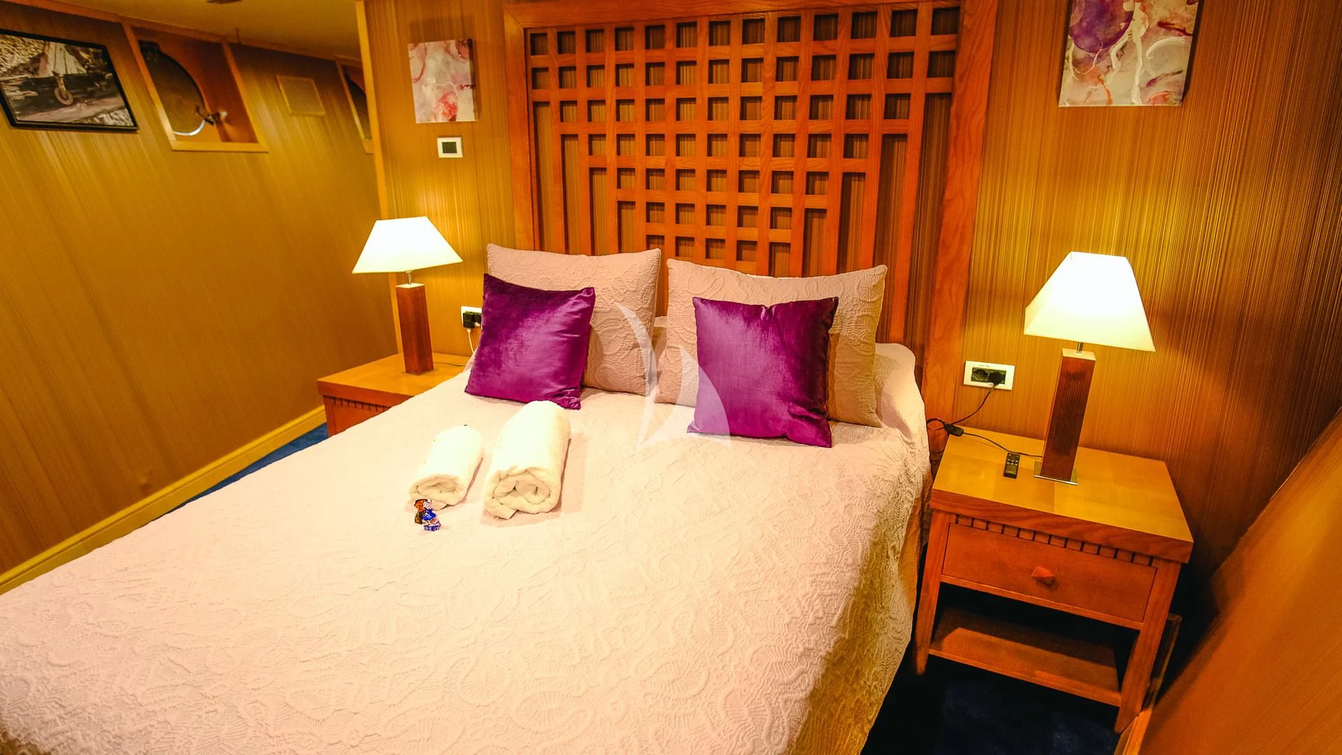 a bed with a white sheet and pink pillows aboard HARMONY II Yacht for Sale