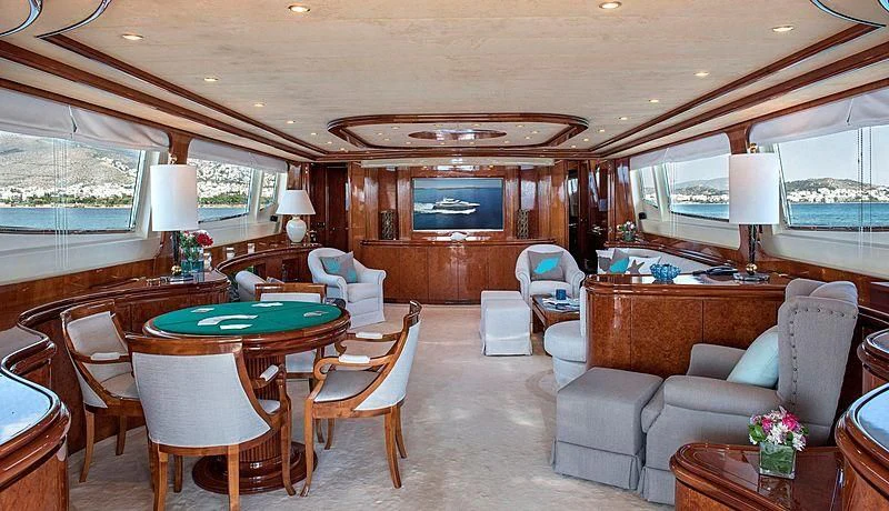 a living room with a large wood dining table and chairs aboard SUGAR Yacht for Sale