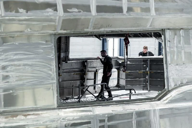 a man standing on a ladder in a large room with a window aboard SPECIAL ONE Yacht for Sale