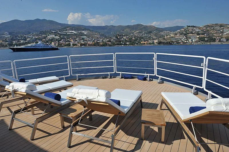a deck with chairs and tables on it aboard OMNIA Yacht for Sale