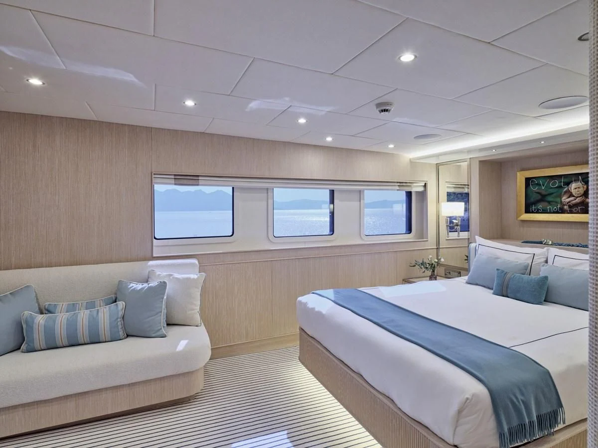 a room with a bed and a couch aboard OMNIA Yacht for Sale