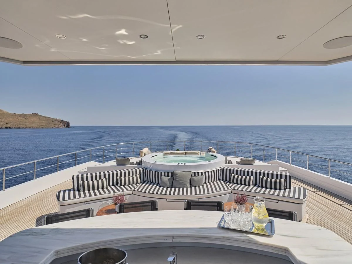 a balcony with a large body of water and a large boat on it aboard OMNIA Yacht for Sale