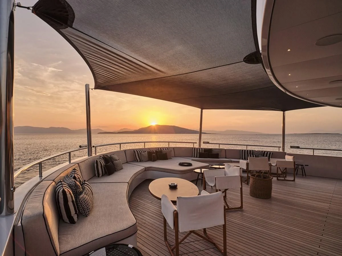 a lounge area with a table and chairs on a deck aboard OMNIA Yacht for Sale