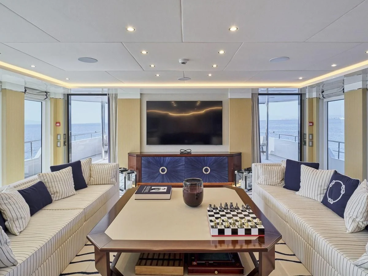 a living room with a tv and a table aboard OMNIA Yacht for Sale