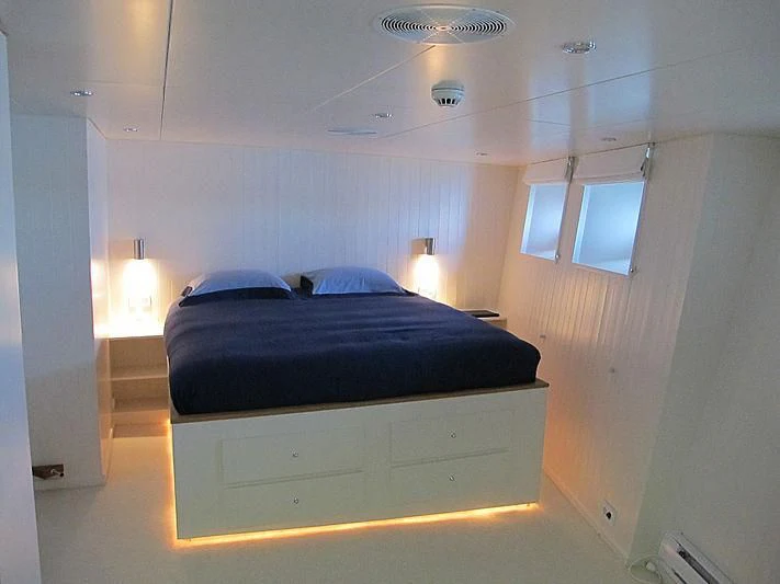 a bedroom with a bed and a window aboard OMNIA Yacht for Sale