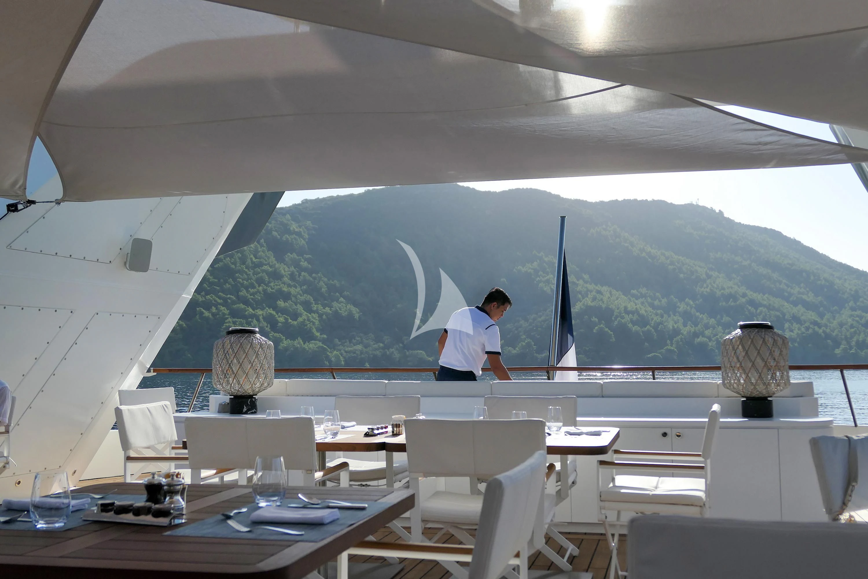 a person sitting at a table in a restaurant with a large mountain in the background aboard LE PONANT Yacht for Charter
