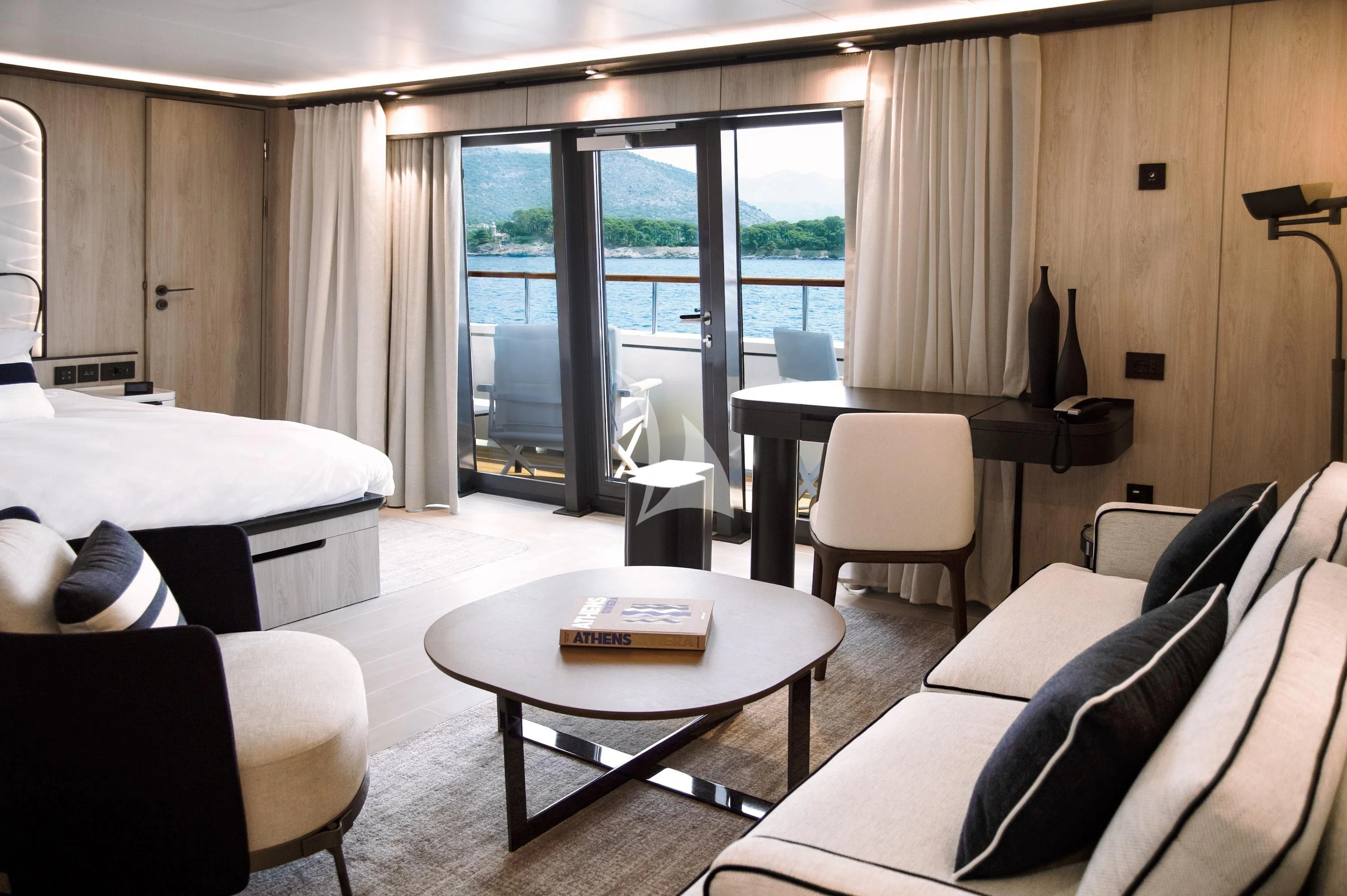 a hotel room with a bed and a table aboard LE PONANT Yacht for Charter
