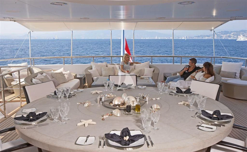 a group of people sitting on a couch on a table with a large body of water behind them aboard HURRICANE RUN Yacht for Charter