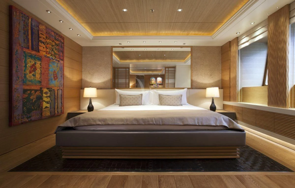 a bed with a painting on the wall aboard NAIA Yacht for Sale