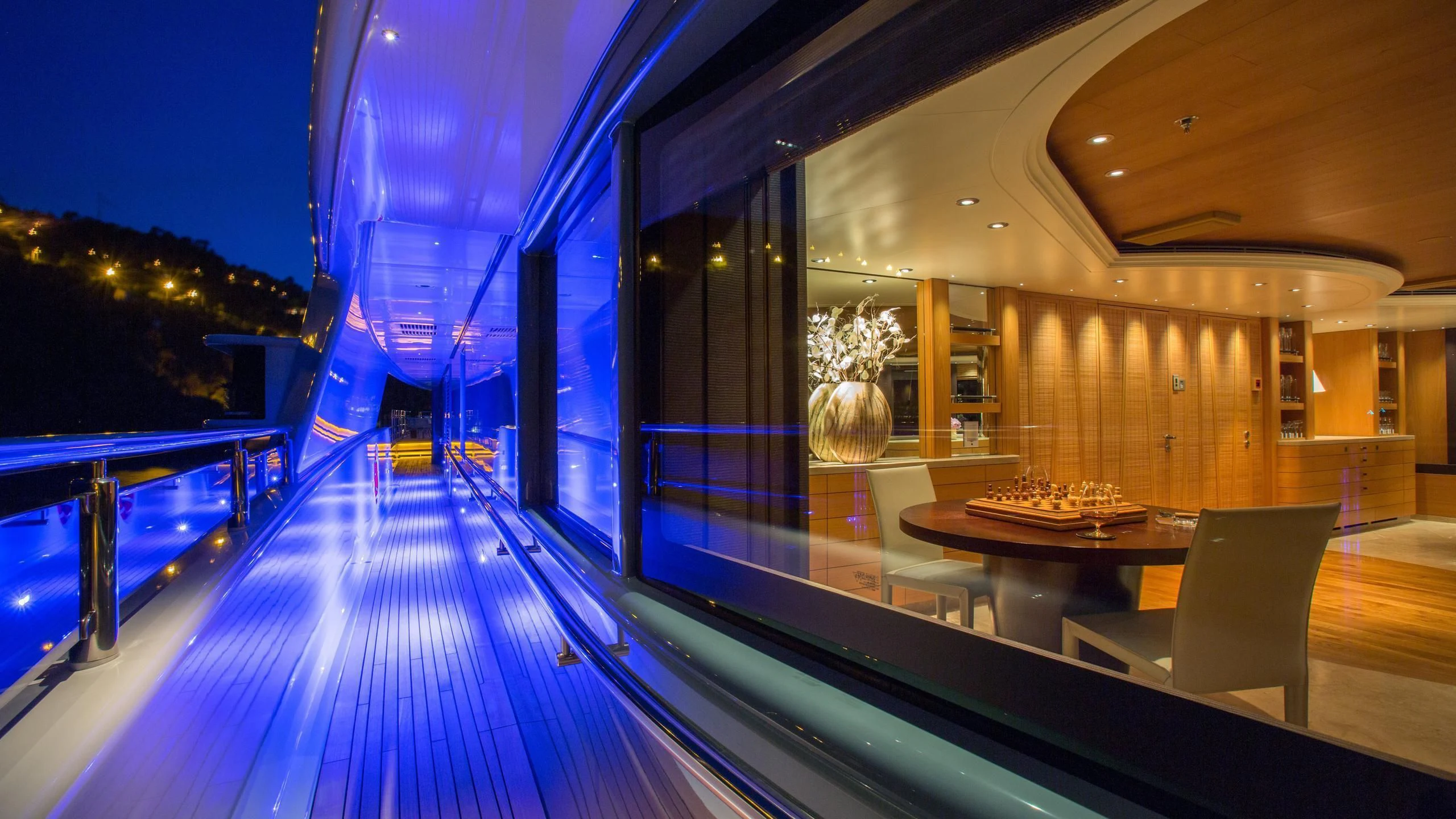 a large lit up pool at night aboard NAIA Yacht for Sale