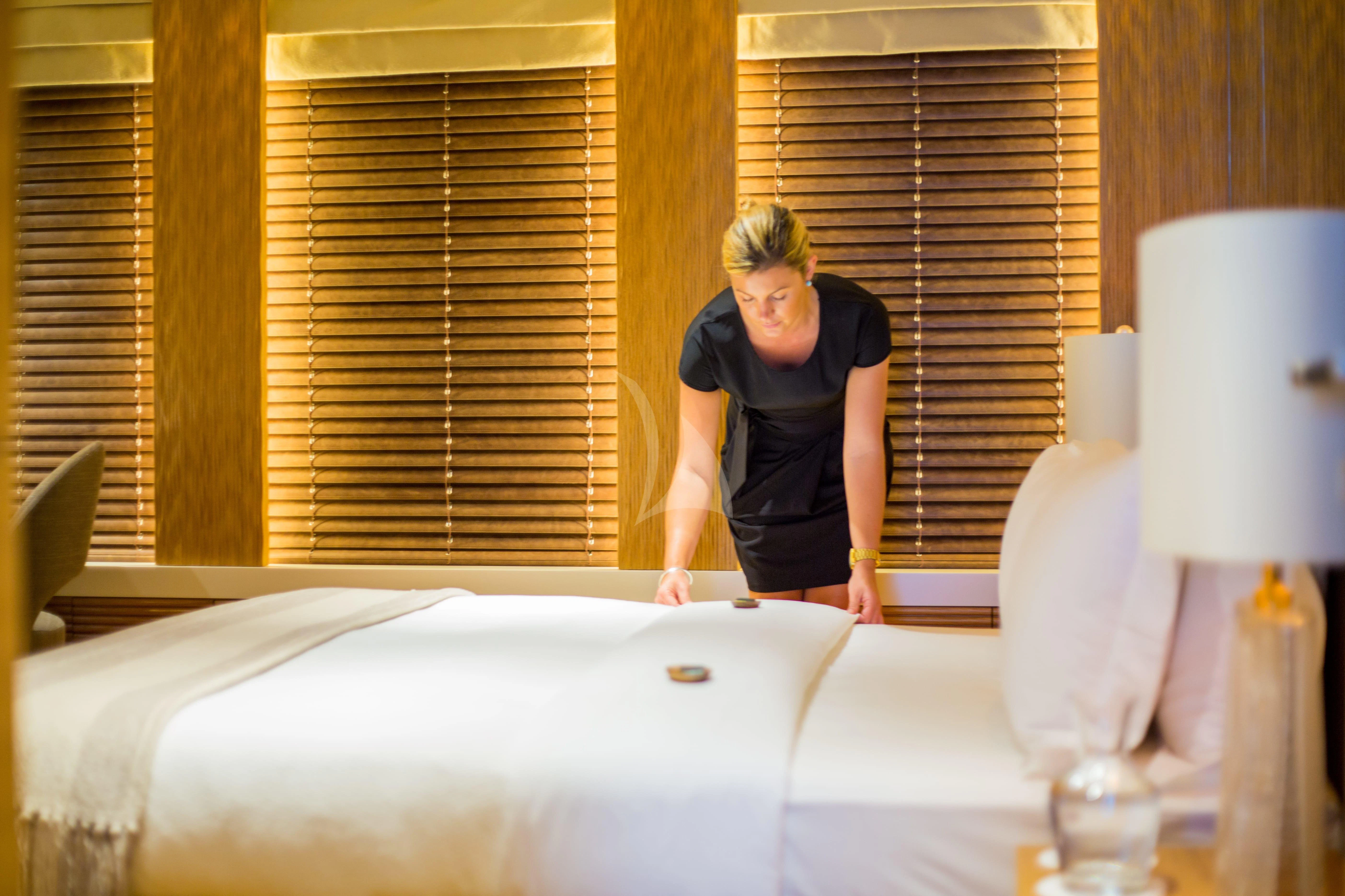 a person standing next to a bed aboard NAIA Yacht for Sale