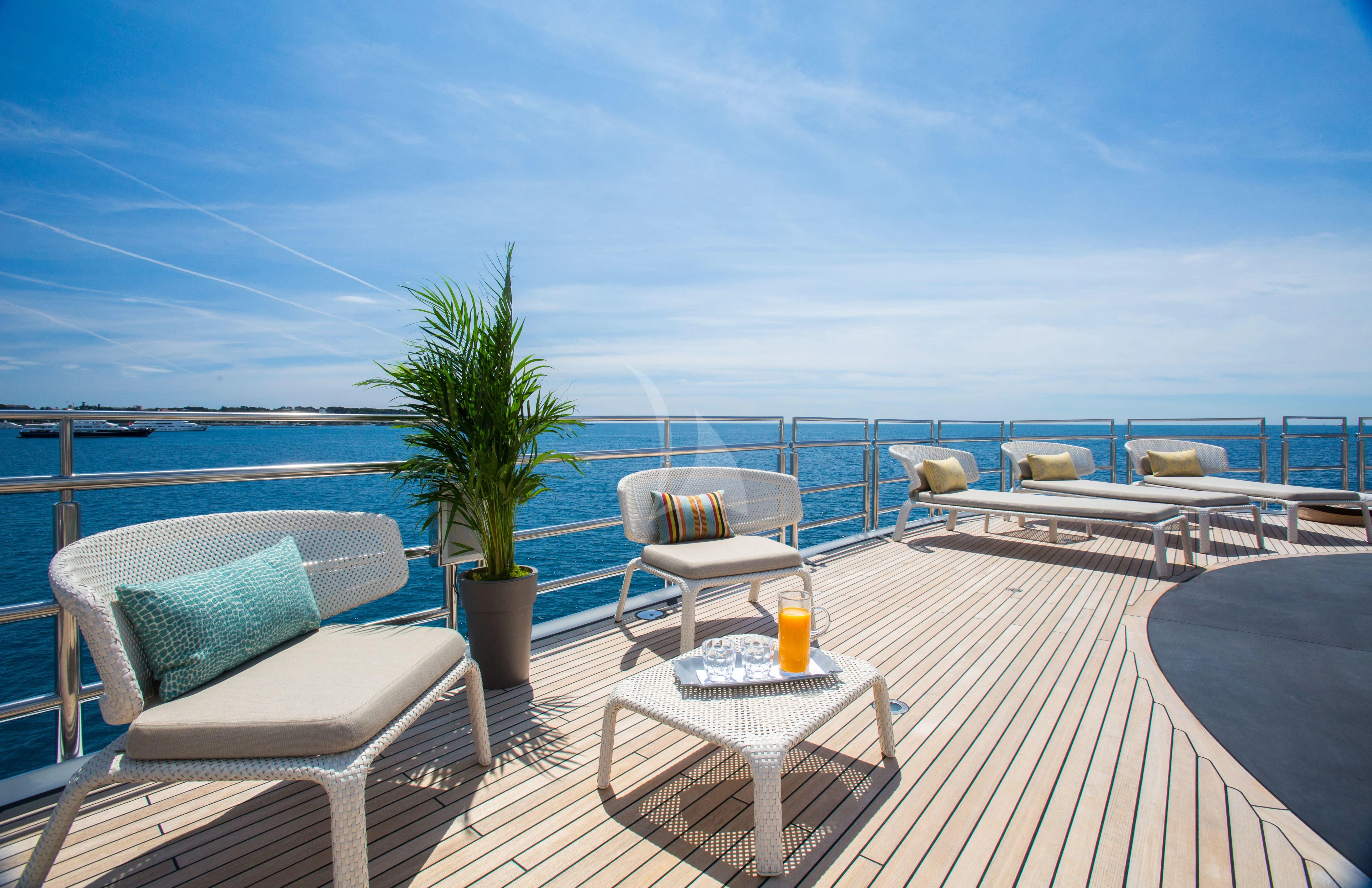 a patio with a table and chairs on it by the water aboard NAIA Yacht for Sale
