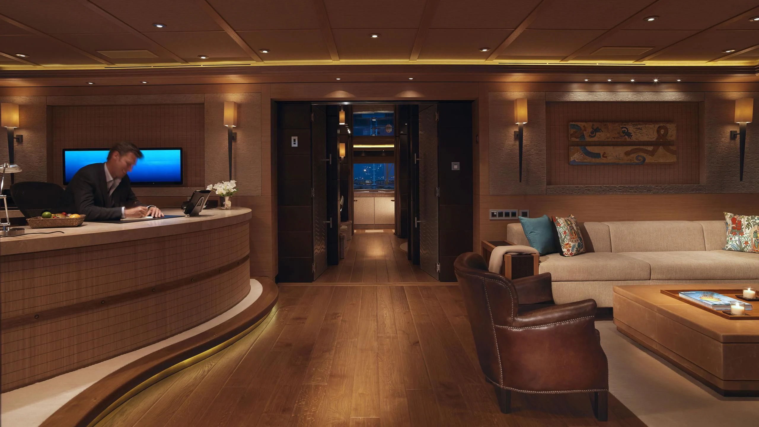 a person sitting at a table in a room with a tv on the wall aboard NAIA Yacht for Sale