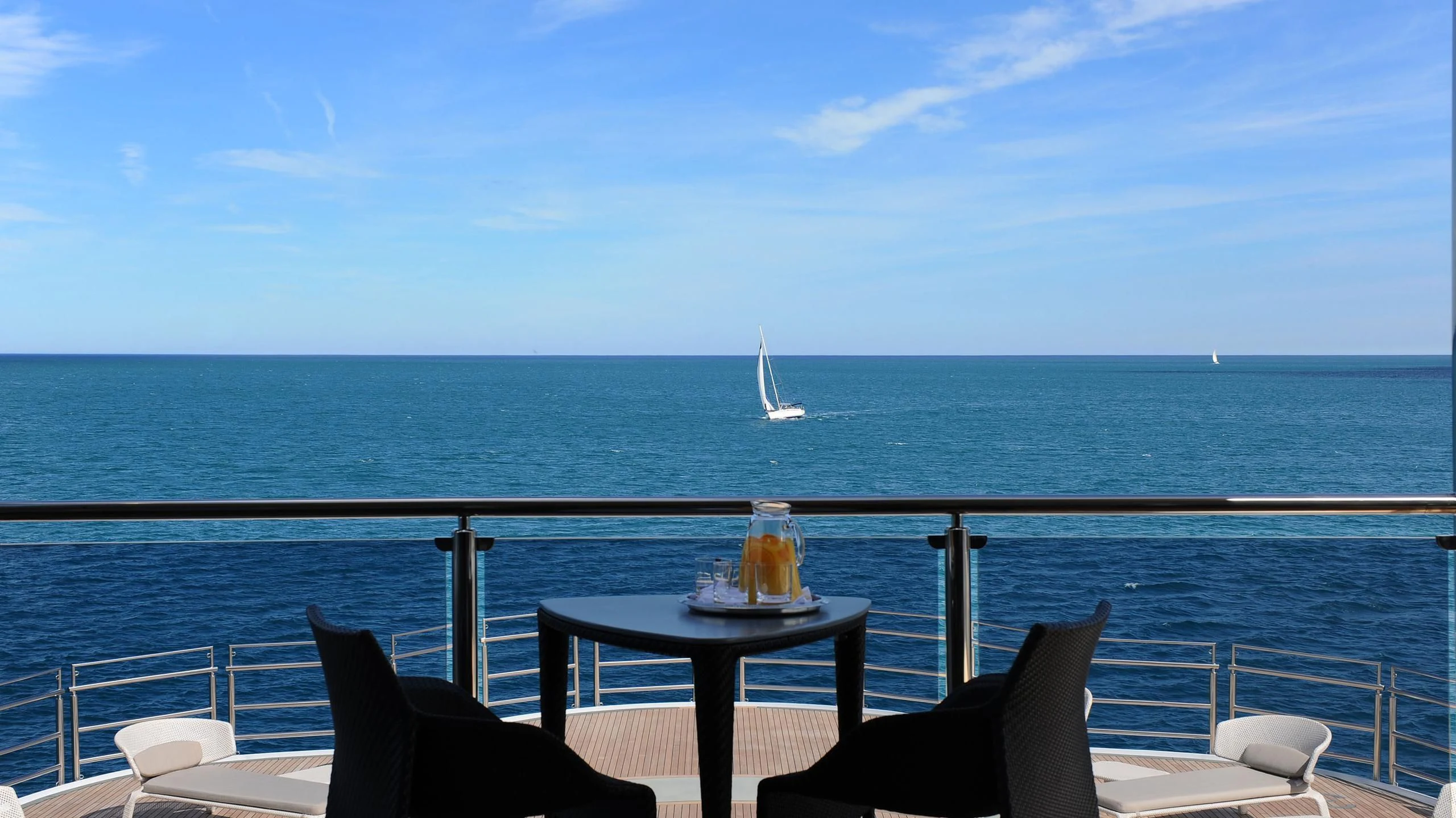 a table on a deck overlooking the ocean aboard NAIA Yacht for Sale