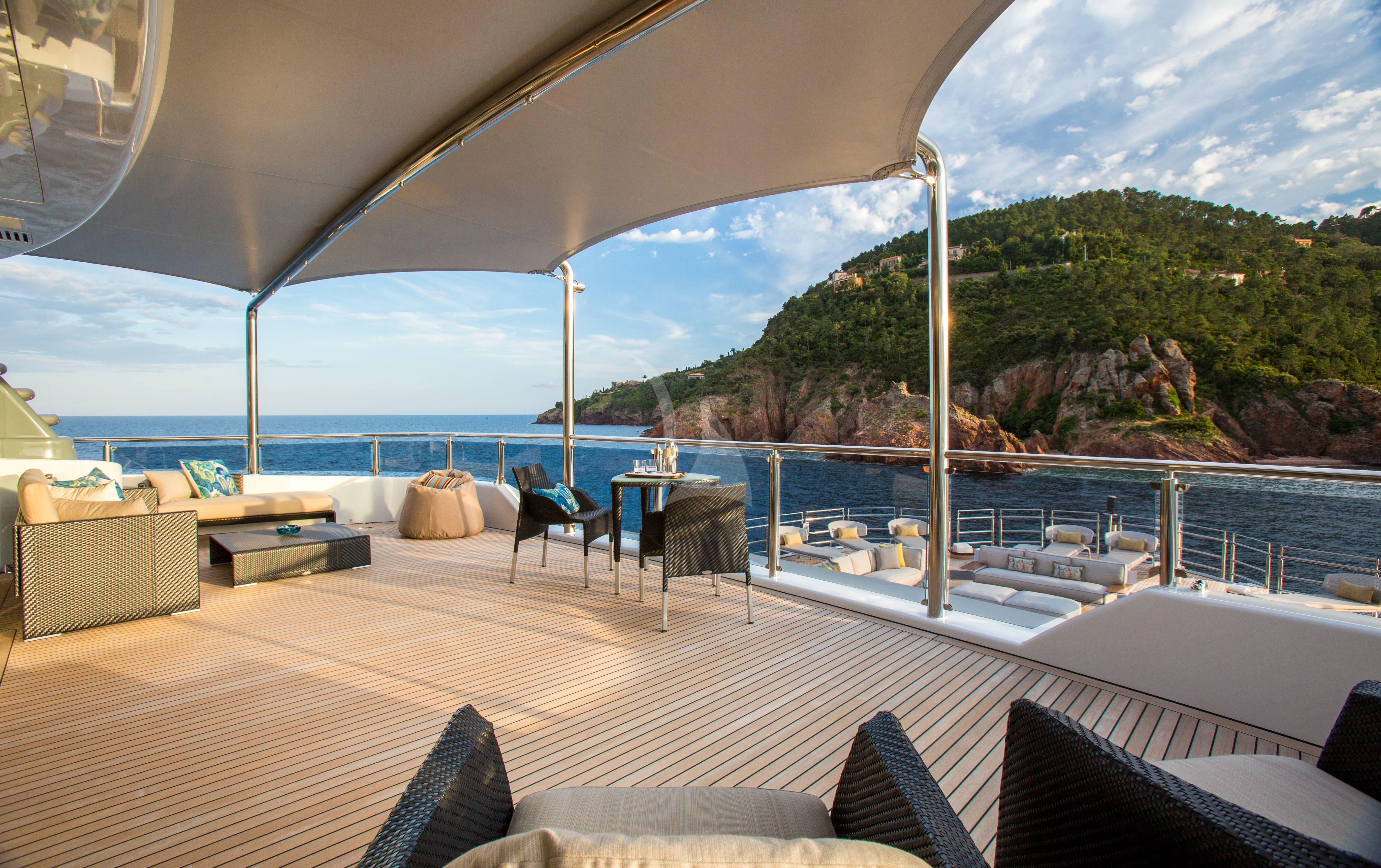 a large white lounge chair on a deck overlooking a large body of water aboard NAIA Yacht for Sale