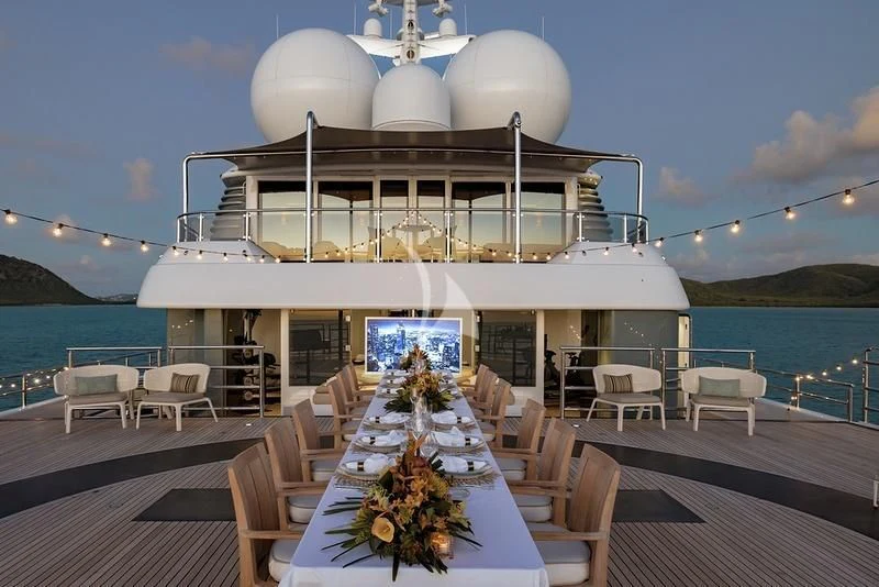 a large white building with a table and chairs on a deck aboard NAIA Yacht for Sale