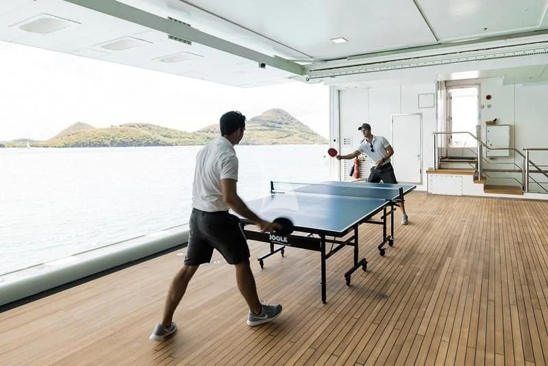 a couple of men playing ping pong aboard NAIA Yacht for Sale
