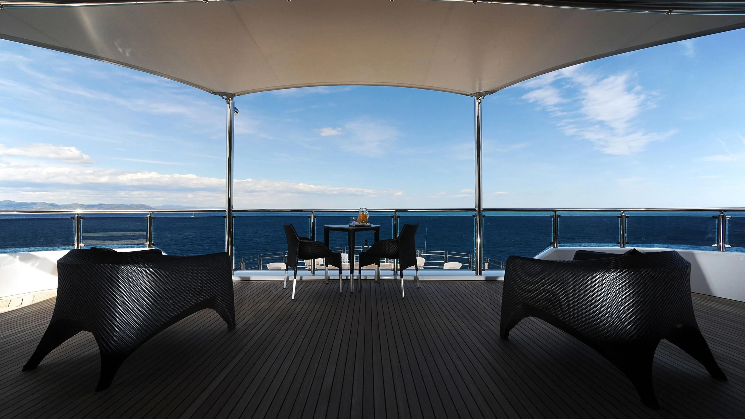 a deck with chairs and a table on it aboard NAIA Yacht for Sale