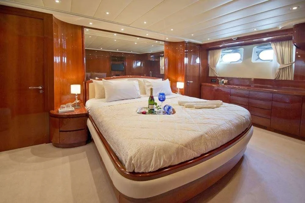 a bed with a white sheet and a bottle of beer on it aboard FALCON ISLAND Yacht for Sale