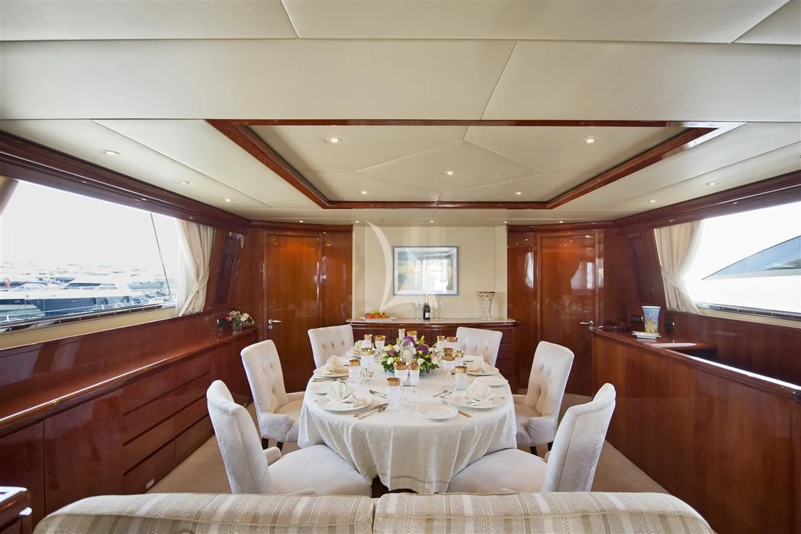 a dining table with chairs and a white table with flowers on it aboard FALCON ISLAND Yacht for Sale