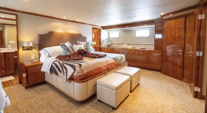 a bedroom with a bed and a wood cabinet aboard WELL DONE Yacht for Sale