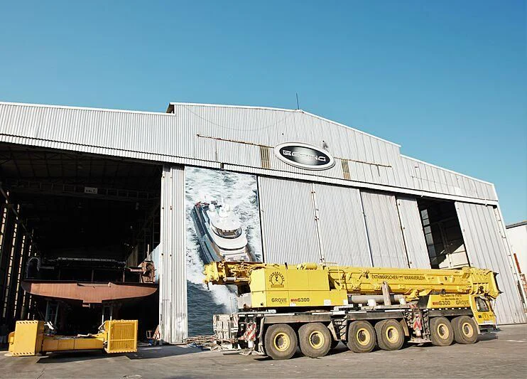 a large white building with a yellow truck parked in front of it aboard HEEUS Yacht for Sale