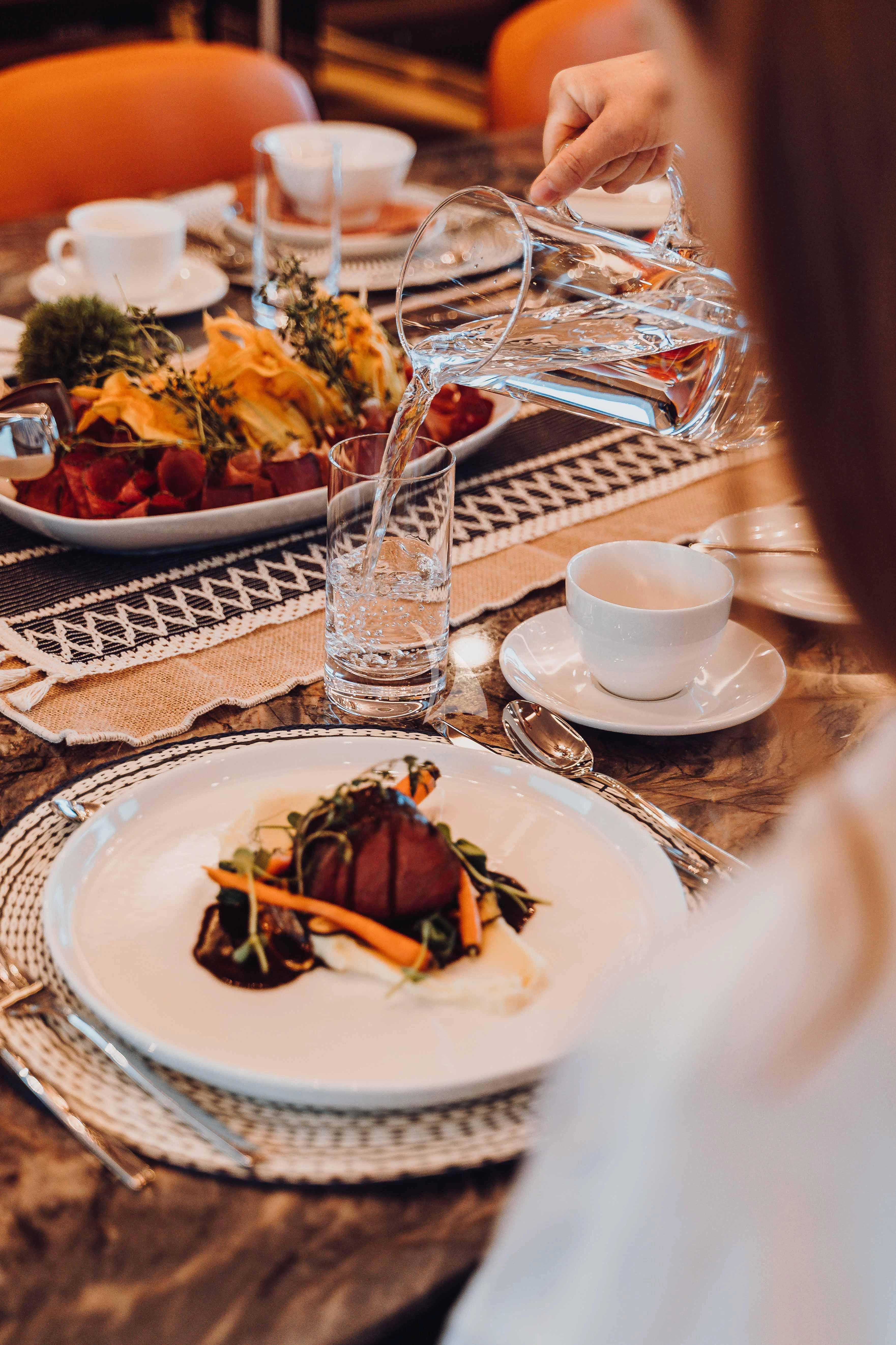 a plate of food and a glass of water on a table aboard HEEUS Yacht for Sale