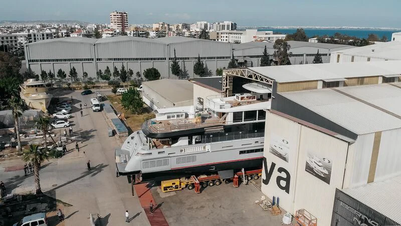 a large white building with a red and black boat parked in front of it aboard HEEUS Yacht for Sale
