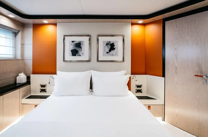 a bed with white sheets and orange walls aboard HEEUS Yacht for Sale