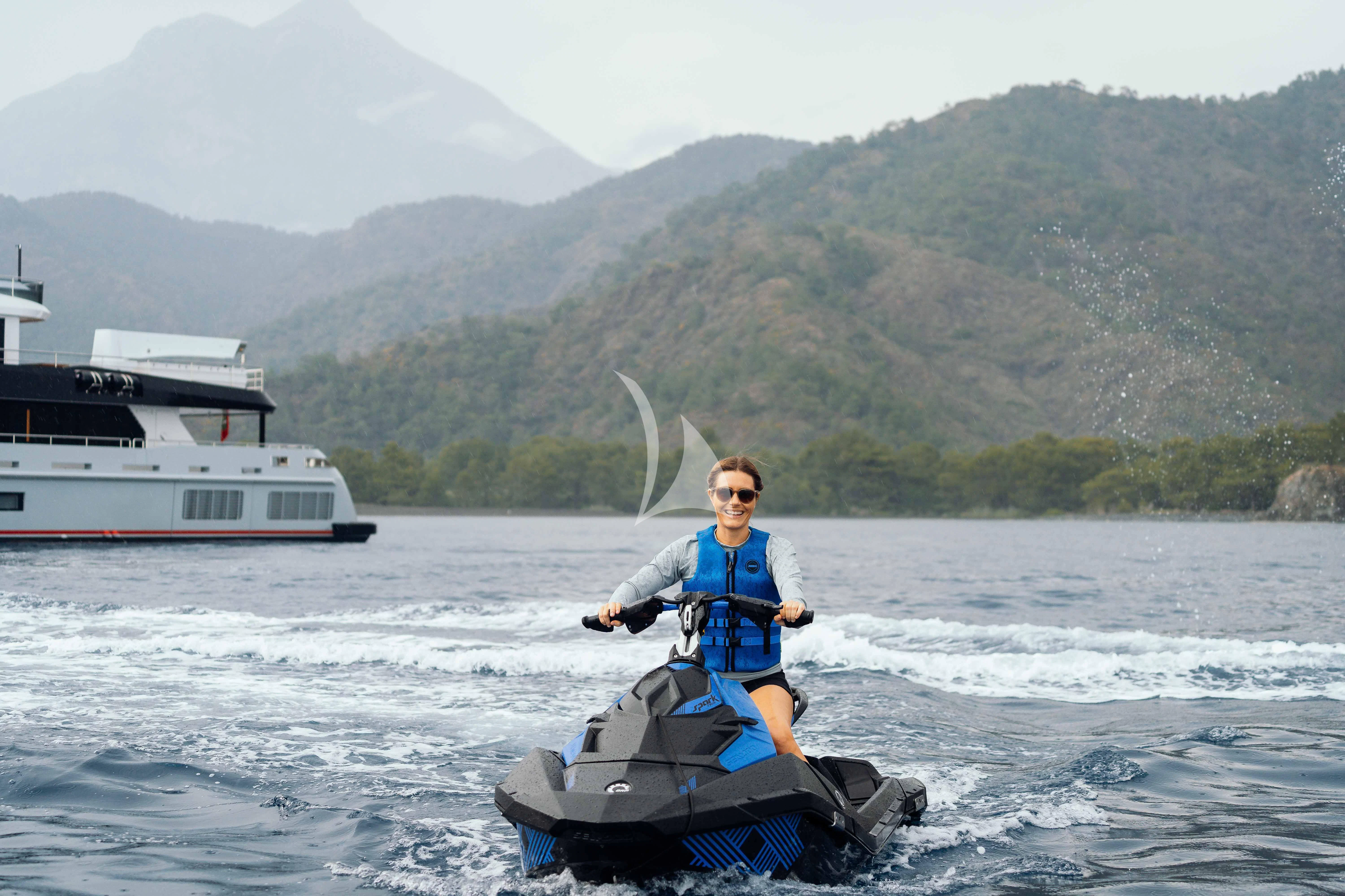 a man riding a jet ski in the water with a boat in the background aboard HEEUS Yacht for Sale