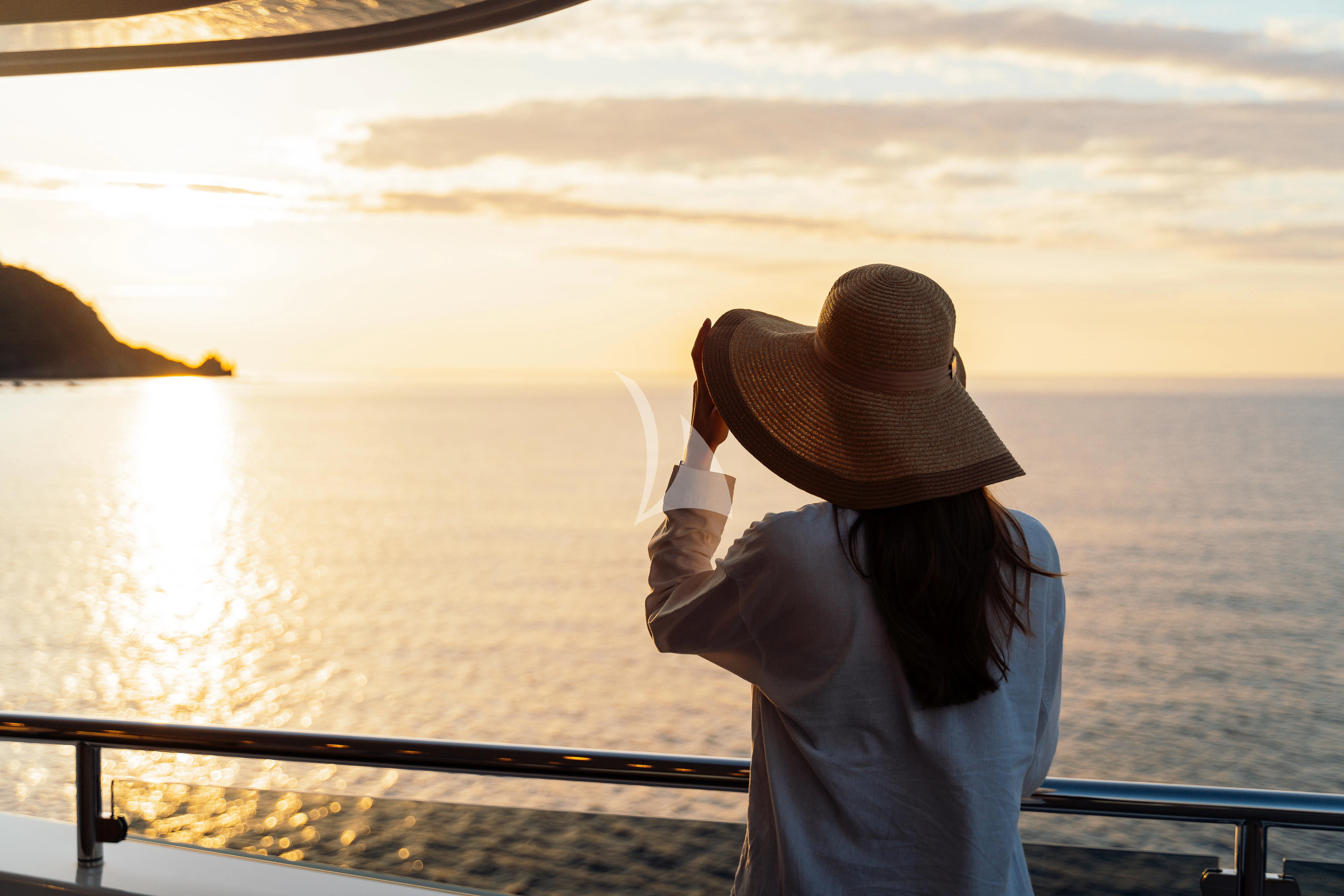 a person wearing a hat looking out at the water aboard HEEUS Yacht for Sale