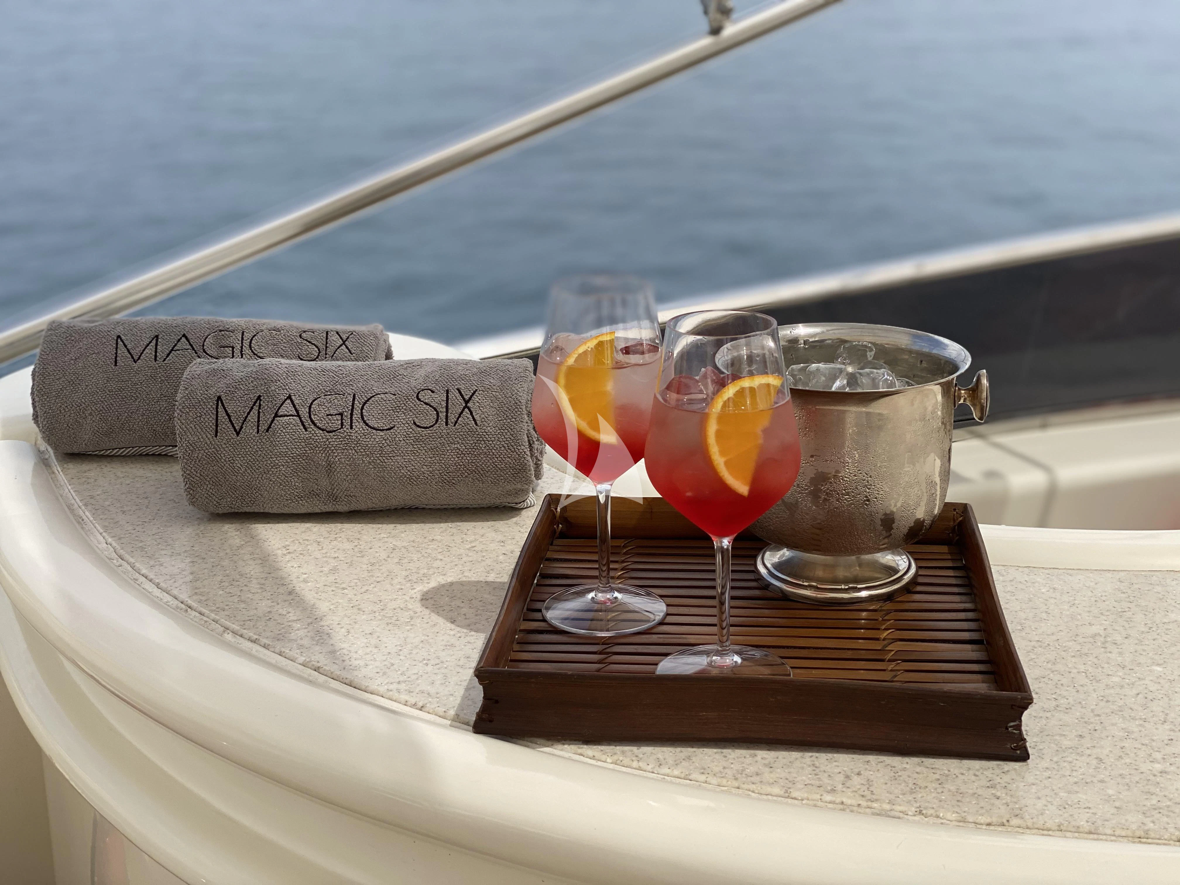 a group of glasses with drinks on a wood table by a sign aboard MAGIC SIX Yacht for Sale