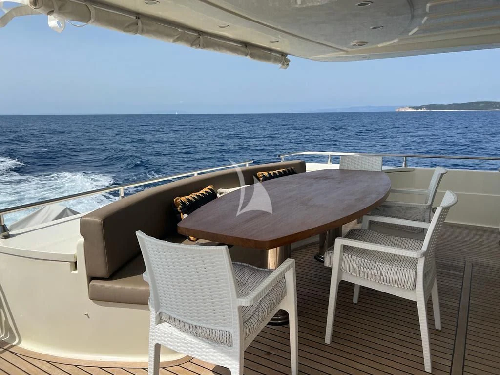 a table and chairs on a deck overlooking a body of water aboard MAGIC SIX Yacht for Sale