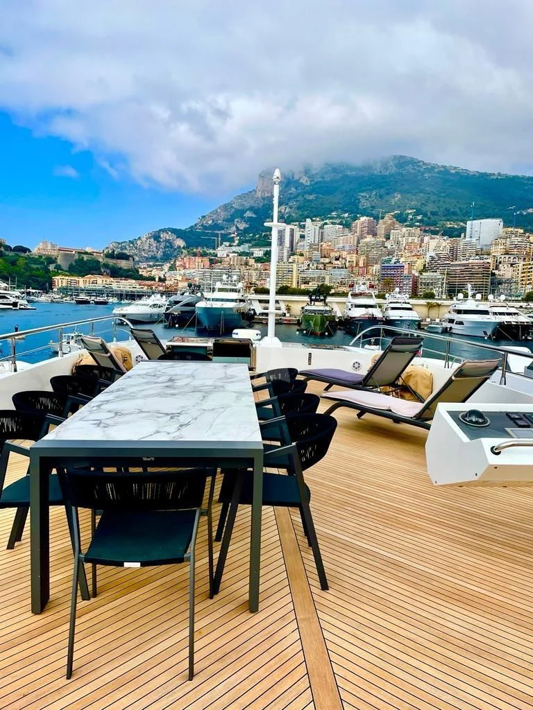 a table and chairs on a deck overlooking a marina with boats aboard FAST & FURIOUS Yacht for Charter