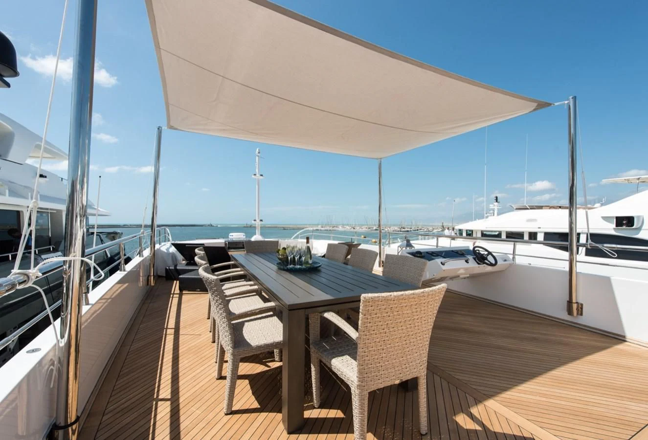 a deck with a table and chairs on it aboard FAST & FURIOUS Yacht for Charter