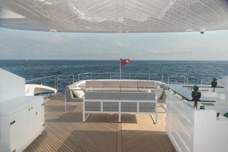 a deck with chairs and tables on it by the ocean aboard FAST & FURIOUS Yacht for Charter