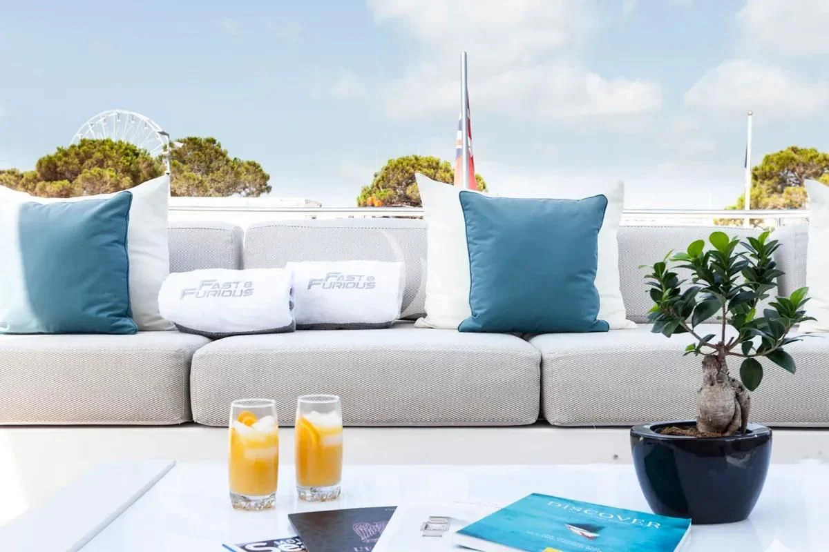 a white couch with blue pillows and a plant on it aboard FAST & FURIOUS Yacht for Charter
